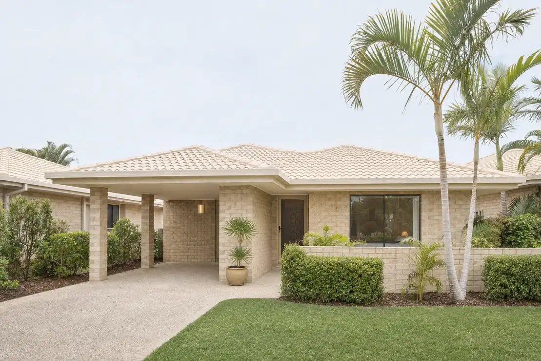 A single storey brick villa in a small quiet complex with a tiled roof, a carport, low hedging and mature palms